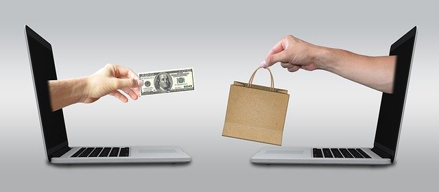 two laptops with hands exchanging cash for a shopping bag